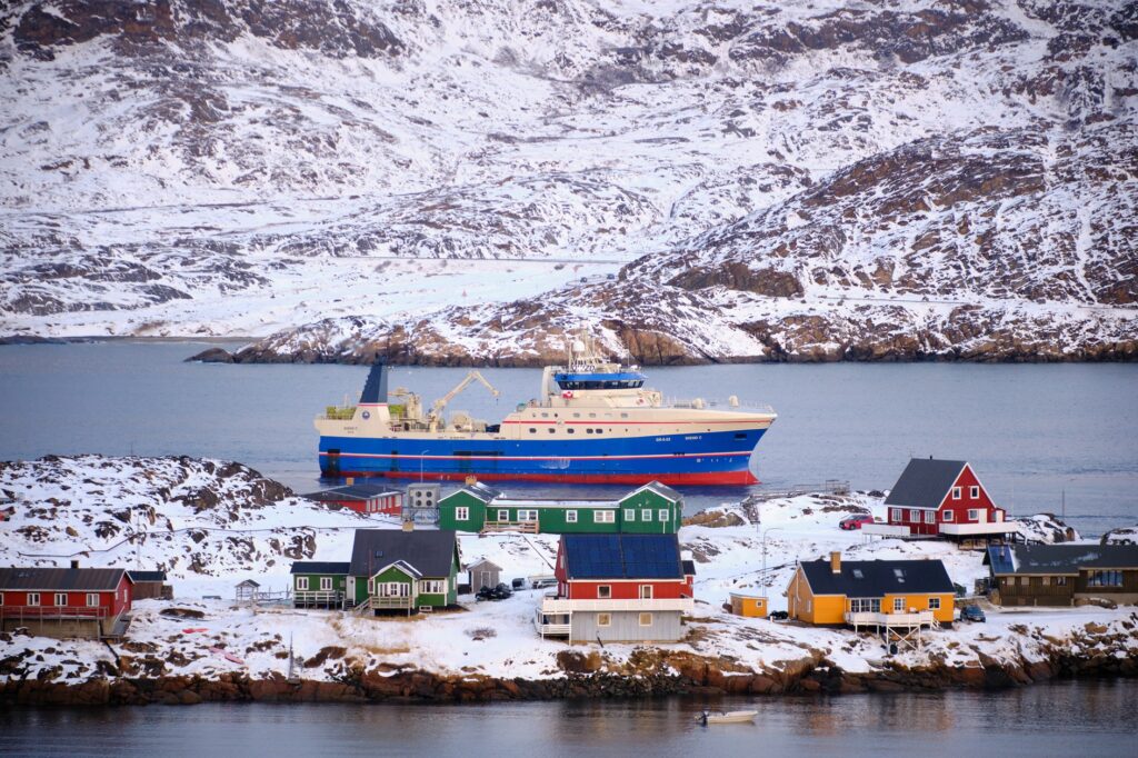 Port of Sisimiut - mid-sized trawler passing colourful houses on its way into port