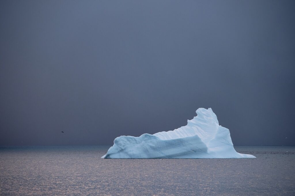 Iceberg floating in calm Arctic water under an overcast sky