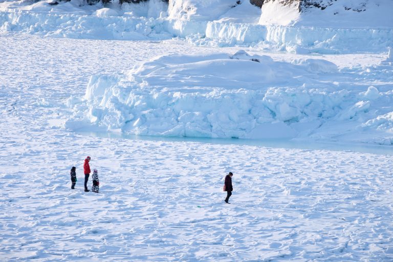 Small figures walking on the frozen sea near Sisimiut
