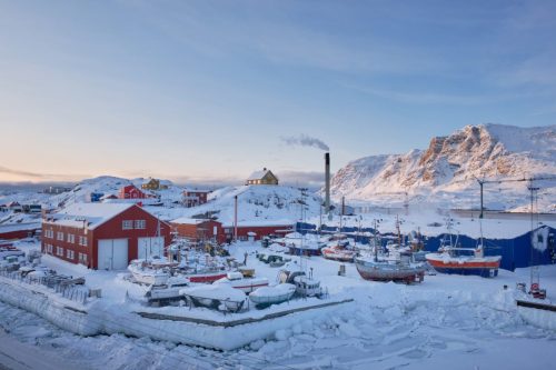 Snow-covered Sisimiut town and harbor with colorful buildings and surrounding mountains.